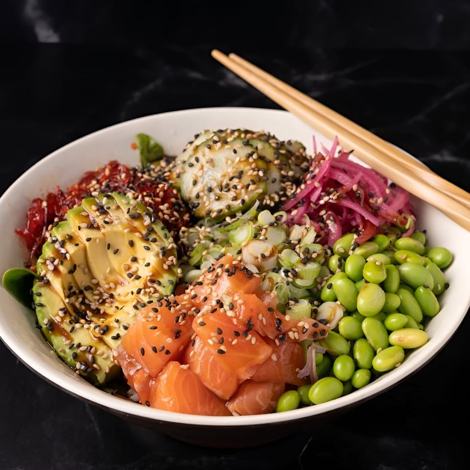 A vibrant Poke-San poke bowl with salmon, avocado, edamame, and pickled onions, topped with sesame seeds.