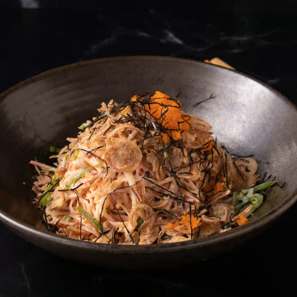 Poke-San poke bowl with noodles, crispy toppings, green onions, and orange roe in a dark bowl.